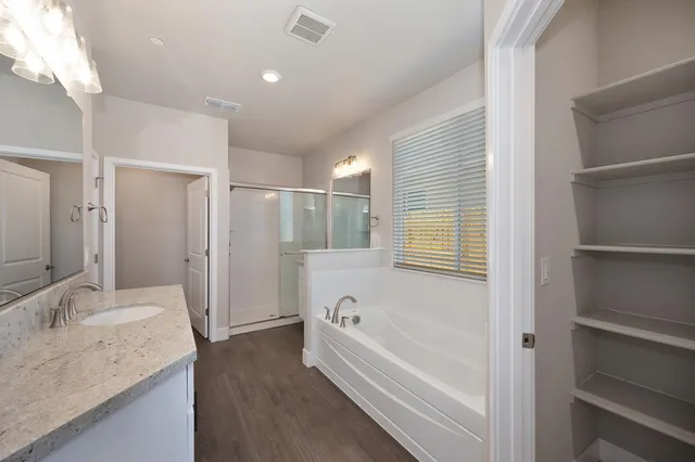 a bathroom with a granite countertop tub sink and mirror