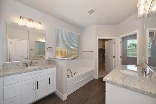 a bathroom with a granite countertop sink mirror and bathtub