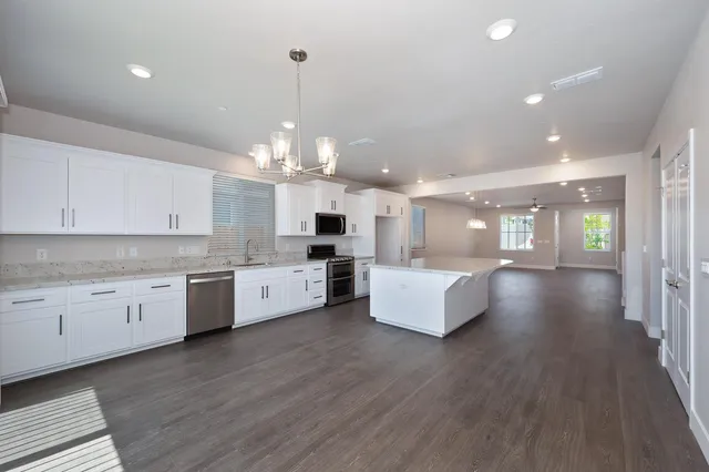 a large white kitchen with lots of counter space wooden floor and appliances