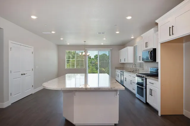 a large kitchen with kitchen island a large counter top space a sink stainless steel appliances and cabinets