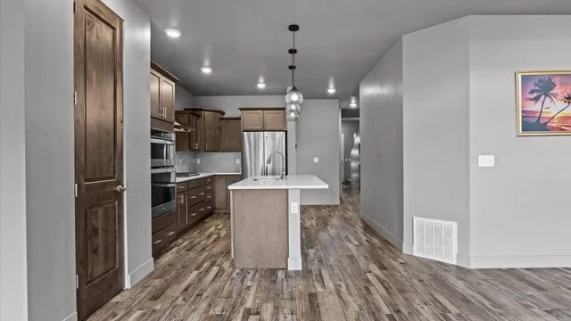 a kitchen with stainless steel appliances granite countertop a refrigerator a oven a sink and a island with wooden floor