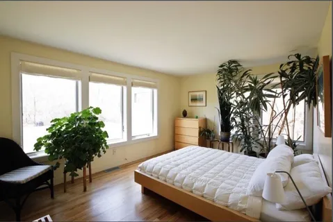 a bedroom with a bed window and a chair