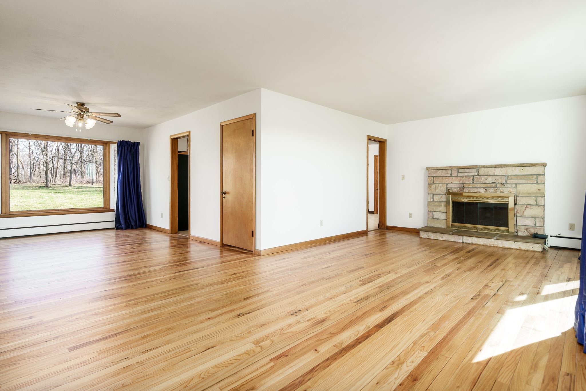 12407 Montague Road Winnebago, IL 61088 - Photo 9 of 43 an empty room with wooden floor fireplace and windows