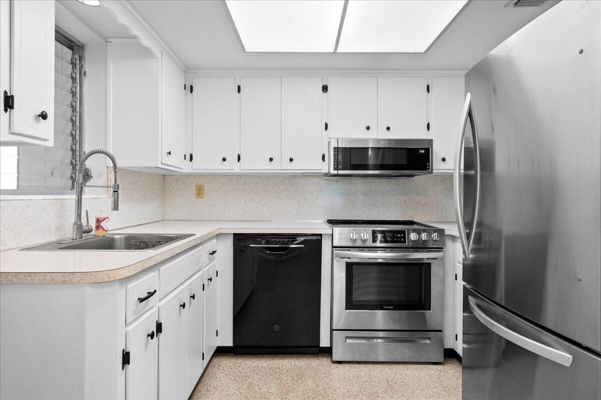606 Pinegrove Avenue Jupiter, FL 33458 - Photo 5 of 11 a kitchen with granite countertop white cabinets and stainless steel appliances