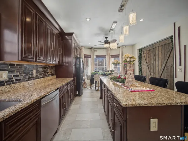 a kitchen with granite countertop kitchen island stainless steel appliances a sink stove top oven and cabinets