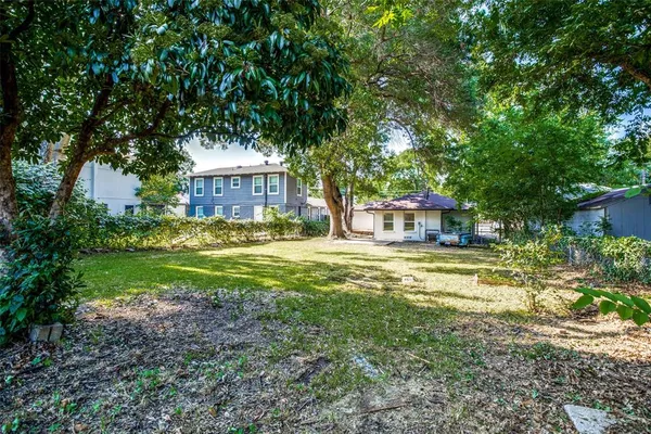a view of a house with a yard and large tree
