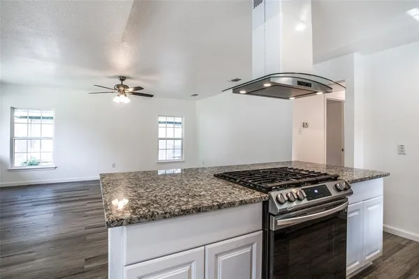 a kitchen with stainless steel appliances granite countertop a stove and a wooden floors