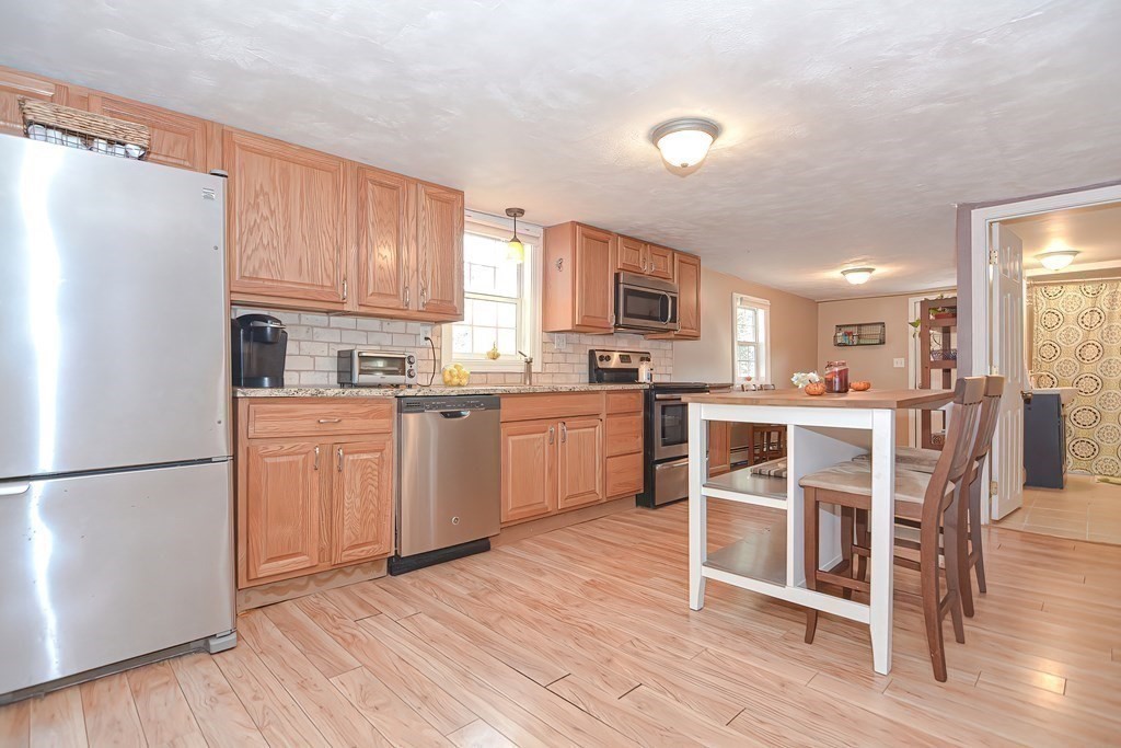 9 Bridge Street Grafton, MA 01536 - Photo 5 of 34 a kitchen with kitchen island granite countertop wooden floors white appliances and cabinets