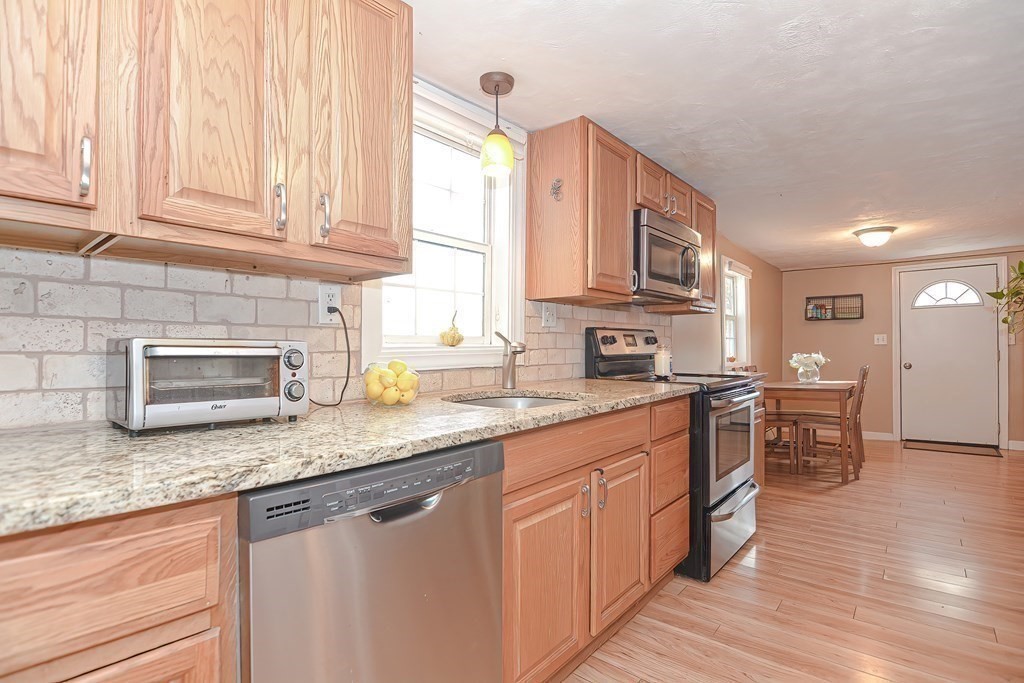 9 Bridge Street Grafton, MA 01536 - Photo 6 of 34 a kitchen with stainless steel appliances granite countertop a sink dishwasher stove and cabinets with wooden floor