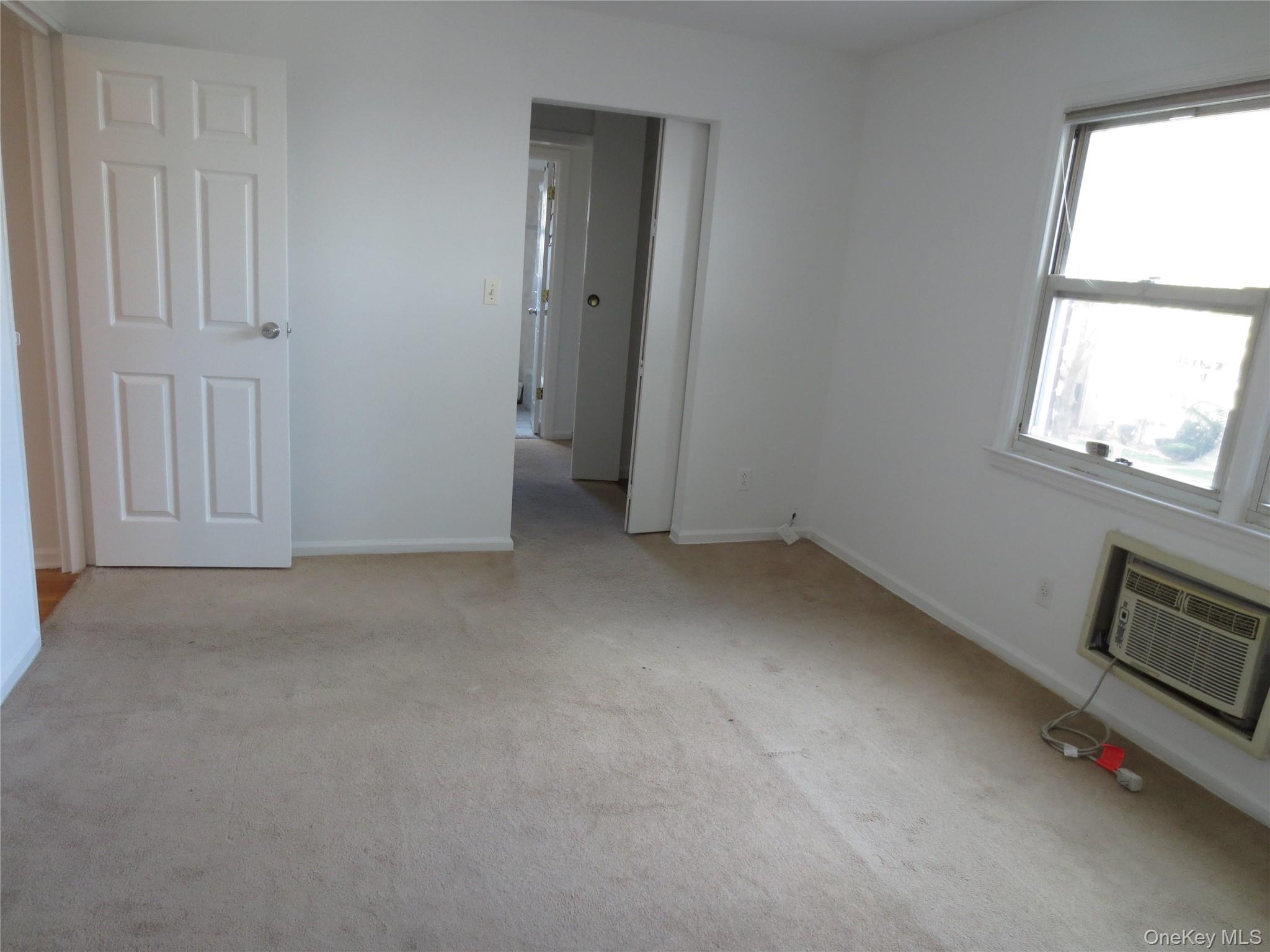 4 Oxford Court, Unit 8007 Suffern, NY 10901 - Photo 12 of 13 Unfurnished bedroom featuring light colored carpet and a wall mounted air conditioner