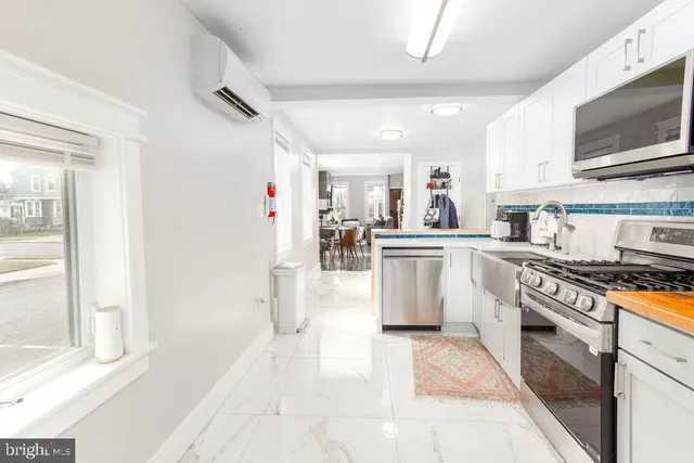a kitchen with stainless steel appliances granite countertop a stove top oven a sink a refrigerator white cabinets and couches with wooden floor