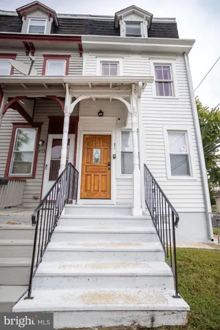 a view of a white house with a large space and a trees