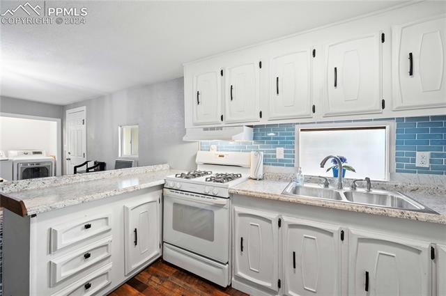 1326 Forest Road Colorado Springs, CO 80906 - Photo 4 of 22 Kitchen with white gas range, custom range hood, dark hardwood / wood-style flooring, sink, and separate washer and dryer