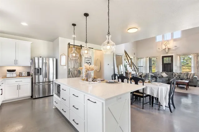 a large kitchen with kitchen island a large island a sink a stove and a chandelier