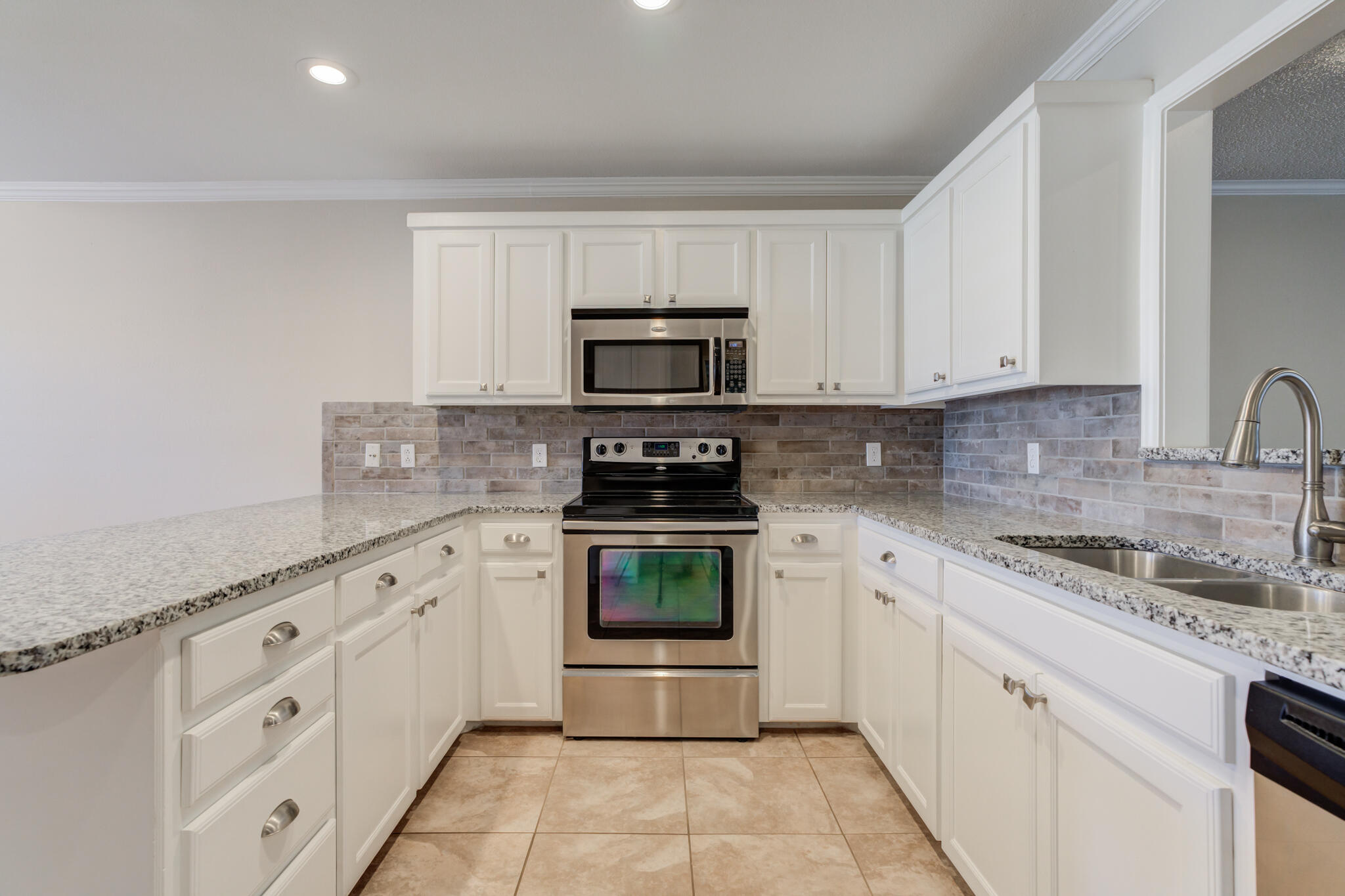 5407 68th Street Lubbock, TX 79424 - Photo 12 of 40 a kitchen with granite countertop white cabinets and stainless steel appliances