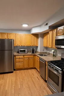 a kitchen with stainless steel appliances granite countertop a stove a sink dishwasher a refrigerator and a microwave oven with wooden floor