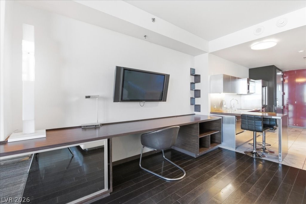 4381 West Flamingo Road, Unit 10306 Las Vegas, NV 89103 - Photo 11 of 26 This open-concept space features rich wood flooring and a sleek kitchen with modern appliances.