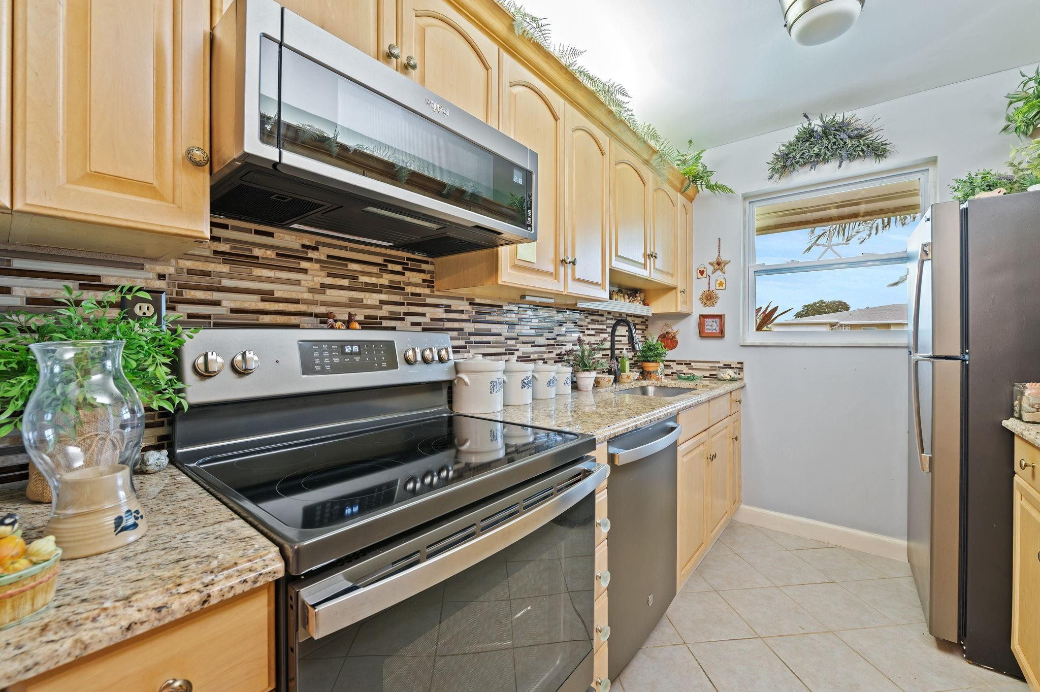 152 High Point Boulevard, Unit D Delray Beach, FL 33445 - Photo 14 of 34 a kitchen with stainless steel appliances granite countertop a stove a sink and a microwave
