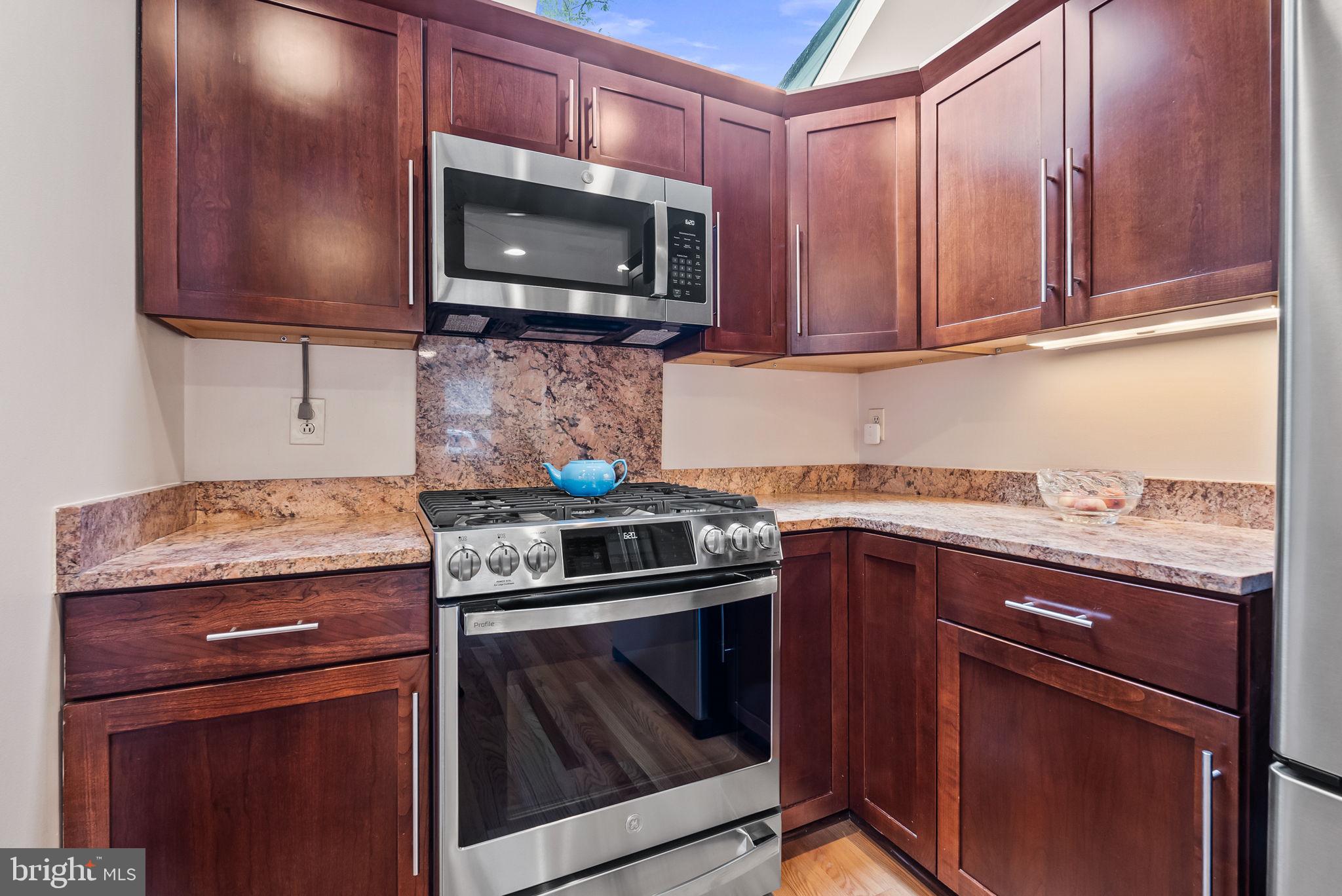 1703 Russell Road Alexandria, VA 22301 - Photo 22 of 42 a kitchen with granite countertop a stove top oven microwave and cabinets