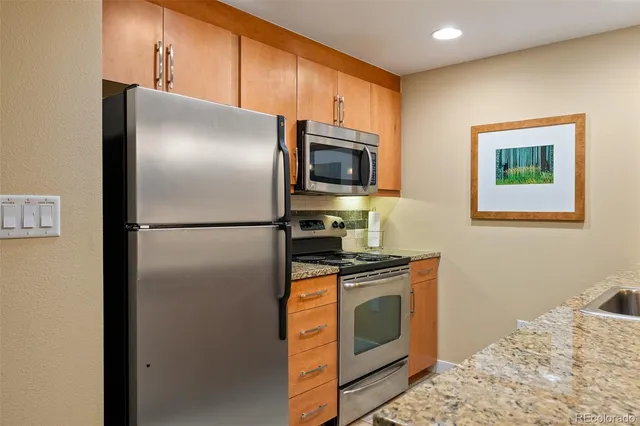 a kitchen with stainless steel appliances granite countertop a refrigerator a stove top oven a sink and dishwasher