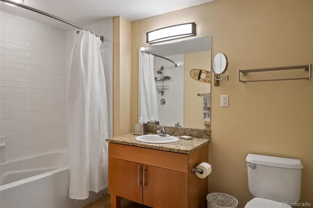 a bathroom with a granite countertop sink toilet and shower