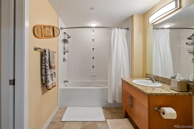 a bathroom with a granite countertop sink a toilet a mirror and shower