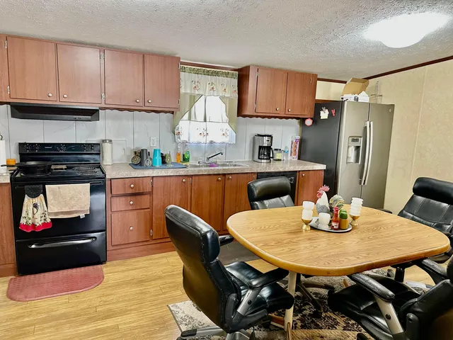 a kitchen with stainless steel appliances a dining table chairs and refrigerator