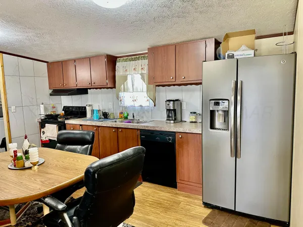 a kitchen with stainless steel appliances granite countertop a refrigerator a sink a stove a dining table and chairs