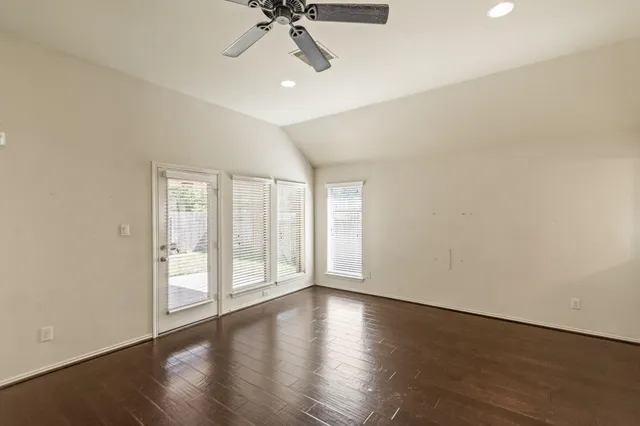 a view of an empty room with a window and wooden floor