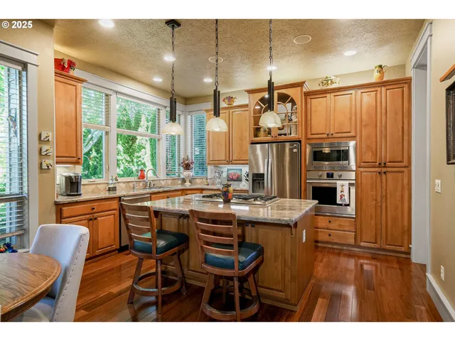 a kitchen with stainless steel appliances granite countertop a sink a stove and a refrigerator