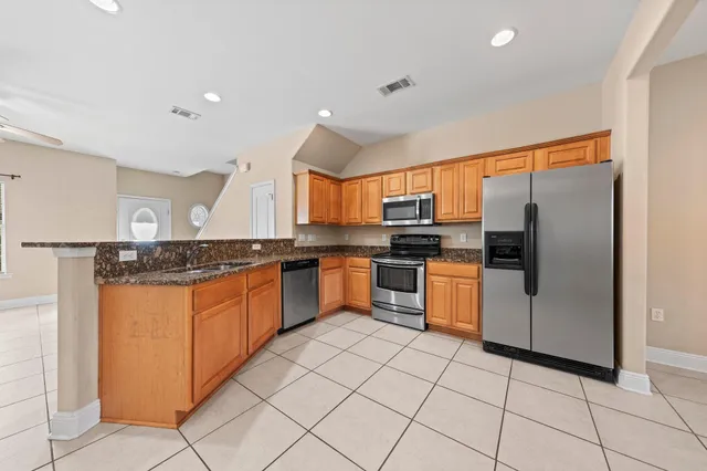 a kitchen with granite countertop a refrigerator and white cabinets