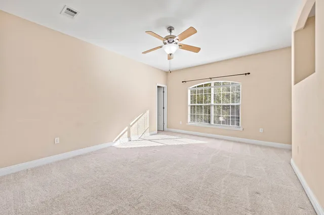 an empty room with windows and fan