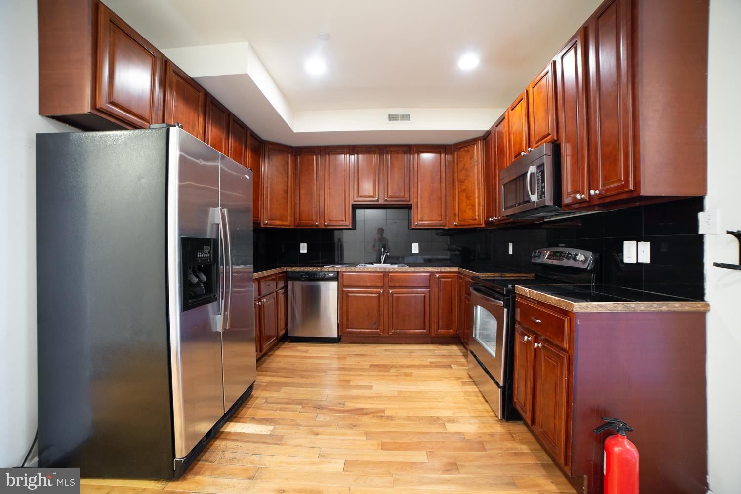 a kitchen with stainless steel appliances granite countertop a refrigerator a sink and wooden cabinets