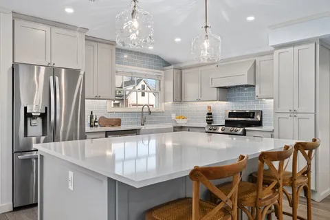 a kitchen with granite countertop a refrigerator a stove a sink a dining table and chairs with wooden floor