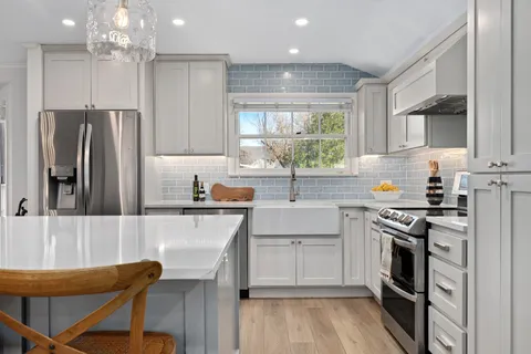 a kitchen with stainless steel appliances granite countertop a stove top oven a sink dishwasher and a refrigerator with wooden floor