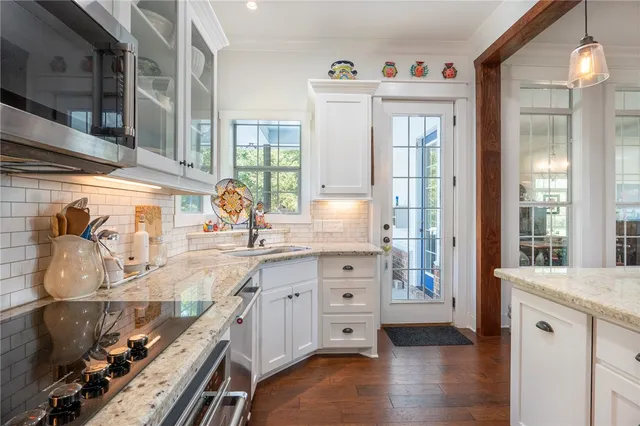 a kitchen with granite countertop a sink cabinets and wooden floor