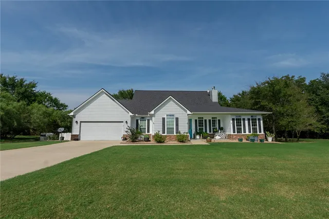 a front view of a house with a garden and trees