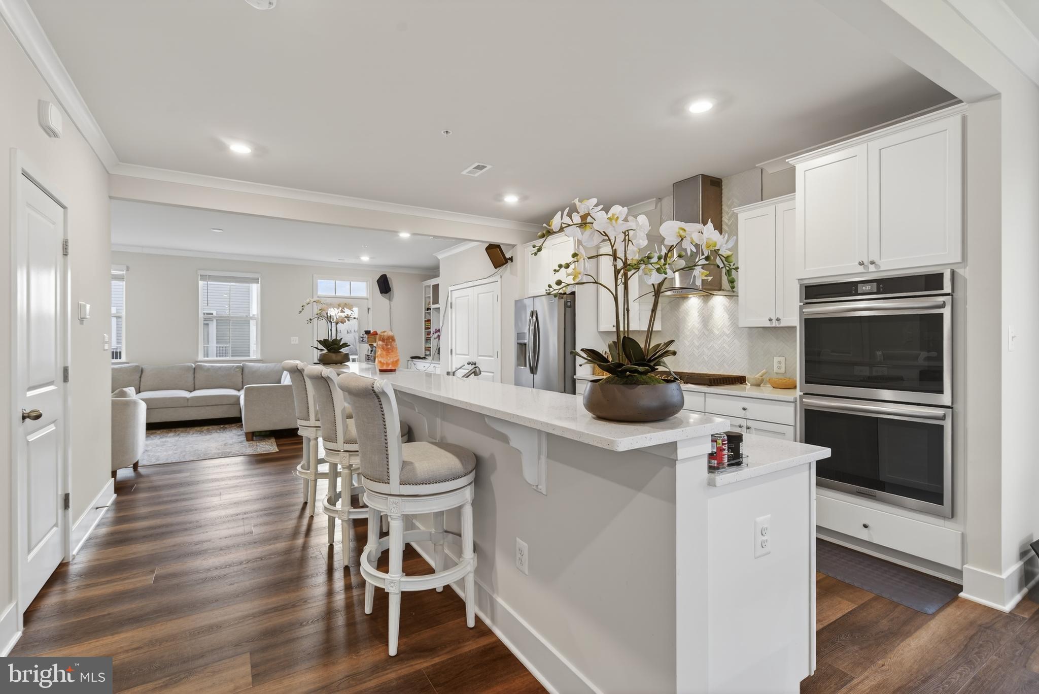 7201 Gringotts Way, Unit B Elkridge, MD 21075 - Photo 11 of 37 a kitchen with stainless steel appliances kitchen island granite countertop a table chairs in it and white cabinets