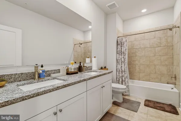 a bathroom with a granite countertop sink a mirror a bathtub and shower