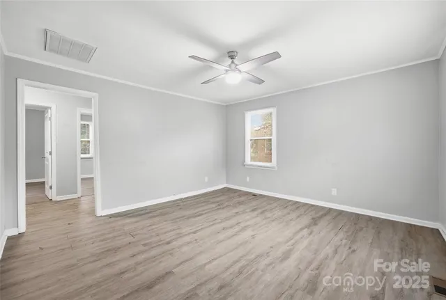 an empty room with wooden floor fan and windows