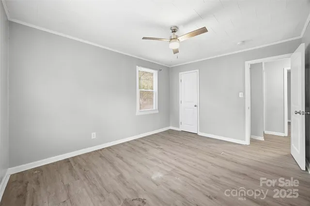 an empty room with wooden floor ceiling fan and windows