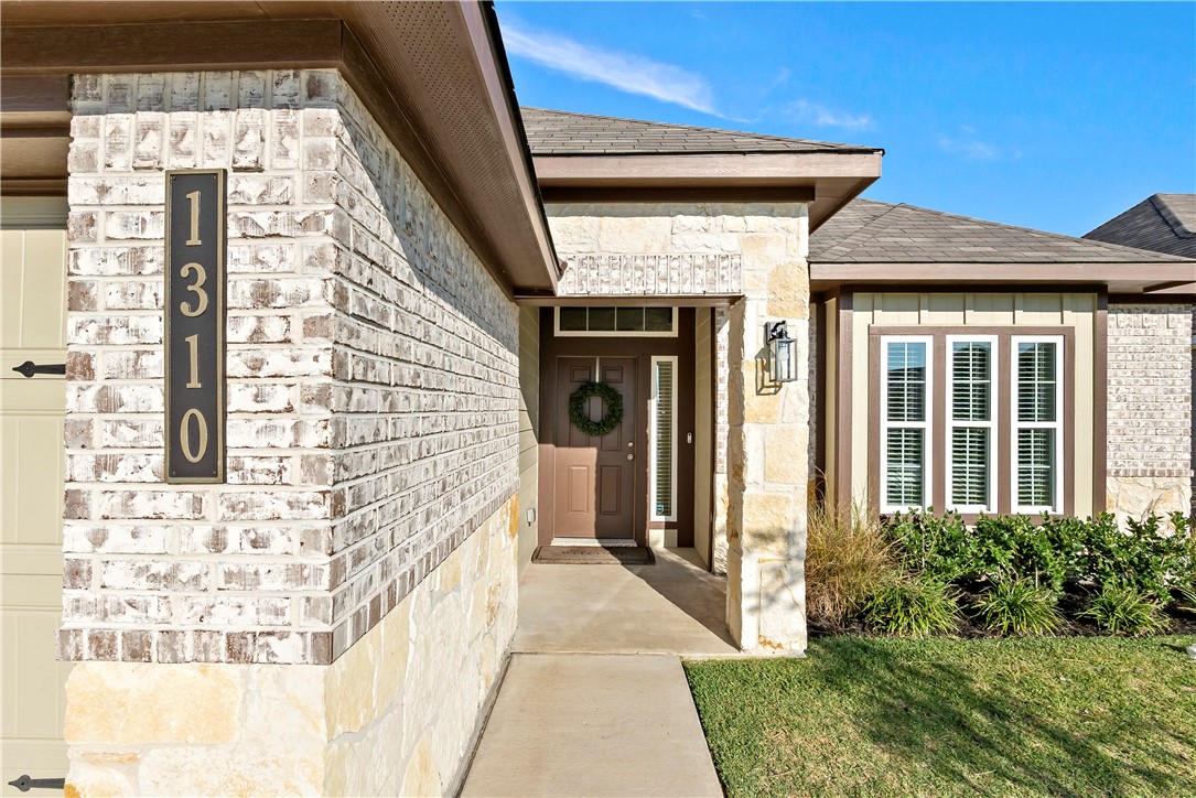 1310 Kingsgate Drive Bryan, TX 77807 - Photo 2 of 24 Property entrance with stone siding, roof with shingles, and a yard