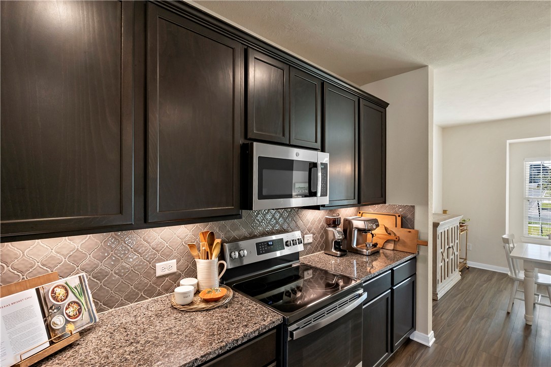 1310 Kingsgate Drive Bryan, TX 77807 - Photo 9 of 24 Kitchen with appliances with stainless steel finishes, dark stone countertops, backsplash, and dark wood-type flooring