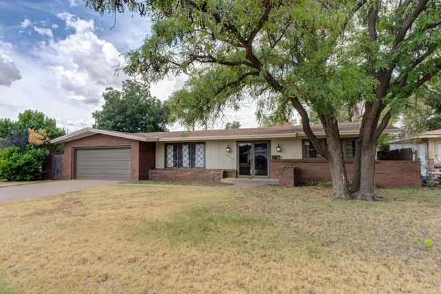 a front view of a house with yard and trees