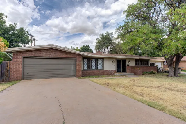 a view of a house with a yard and large tree