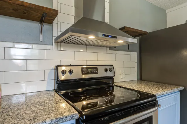 a kitchen with stainless steel appliances granite countertop white cabinets and a window