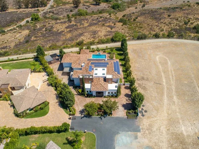 an aerial view of residential houses with outdoor space and trees