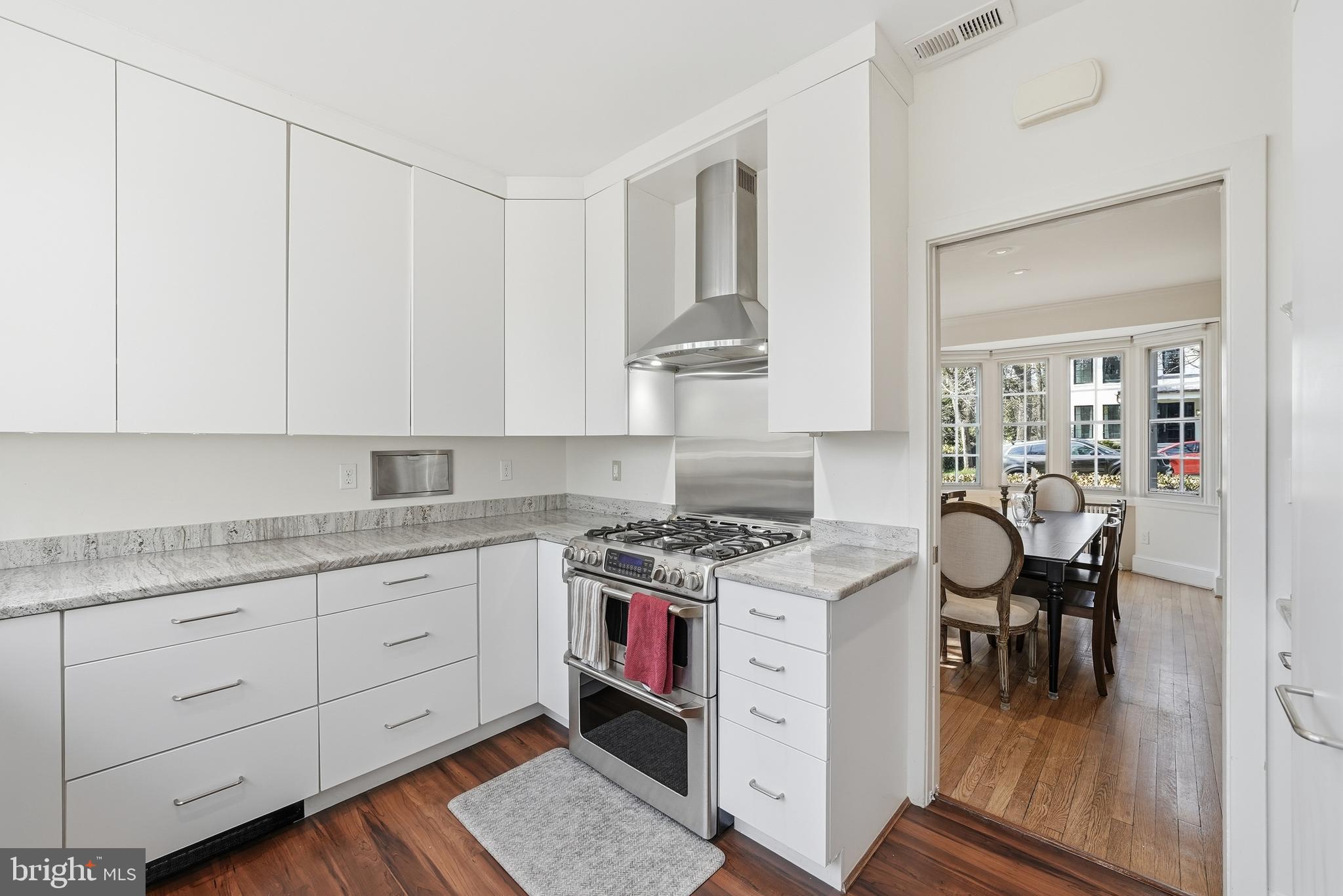 4938 Quebec Street Northwest Washington, DC 20016 - Photo 14 of 51 a kitchen with a stove a sink and white cabinets with wooden floor