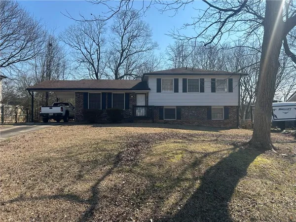 a front view of a house with a yard covered with snow and trees