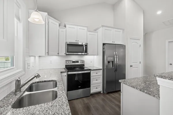 a kitchen with granite countertop a sink wooden cabinets and stainless steel appliances